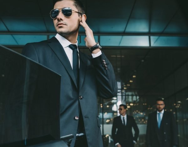 bodyguard-opening-car-door-for-businessman-and-listening-security-earpiece.jpg